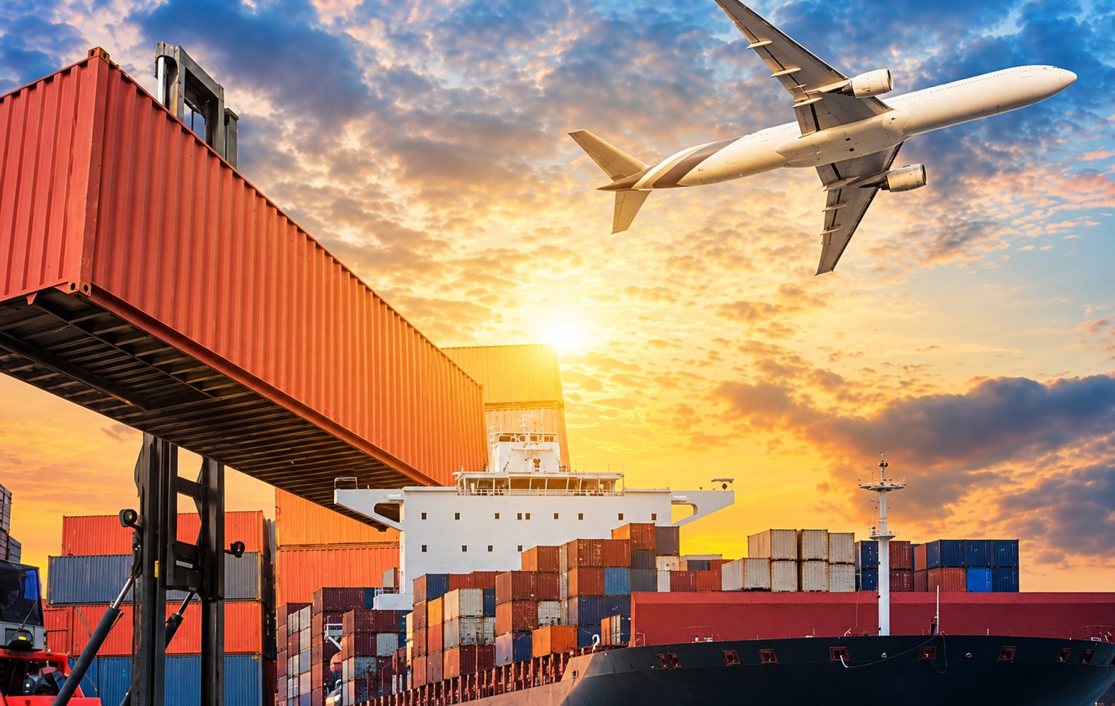 Un conteneur rouge est soulevé au-dessus d'un port tandis qu'un avion survole un navire chargé de conteneurs au coucher du soleil.